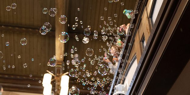 View from below of students blowing bubbles from the Chapel balcony.