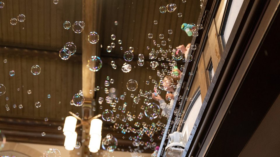 View from below of students blowing bubbles from the Chapel balcony.