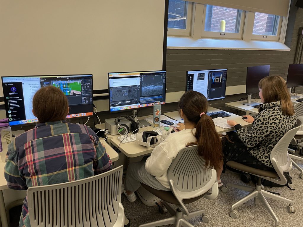 Students sit in front of computers working on the project