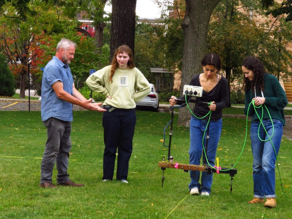A group of people perform an Electrical Resistance Survey on the Chapel lawn.