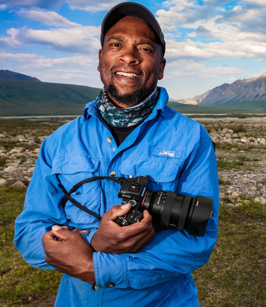 Headshot of Dudley Edmonson, who is holding a camera outdoors.