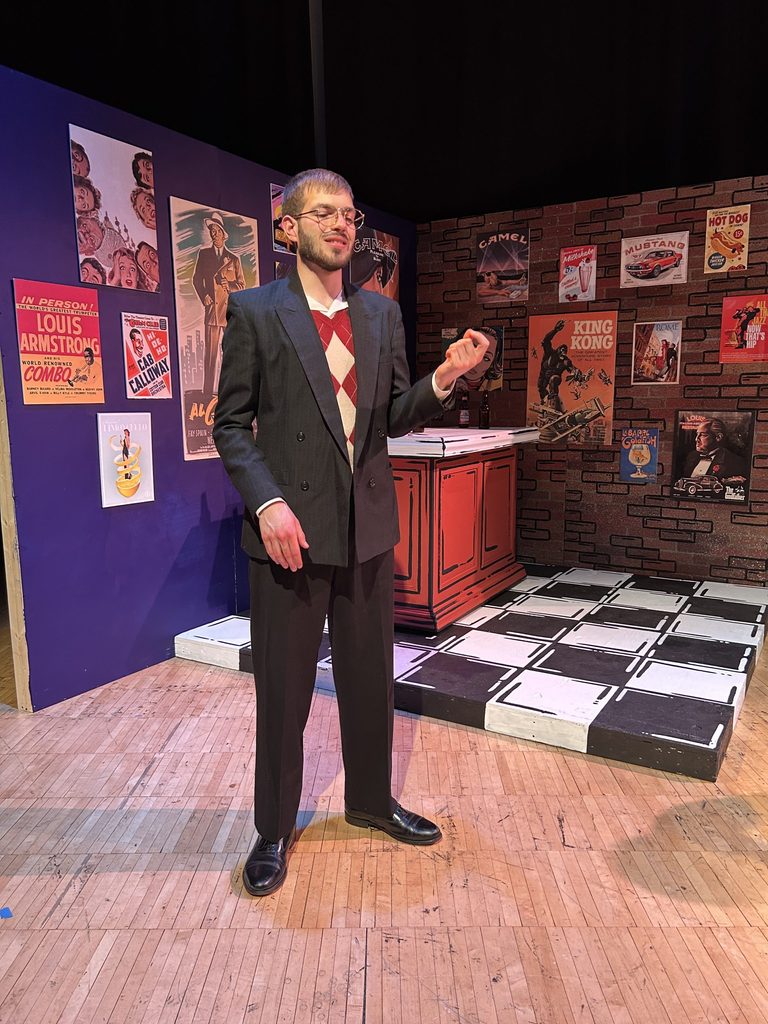 Preves as Louis stands on stage.