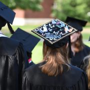 Focus on a student's graduation cap decorated with paper butterflies that reads, 