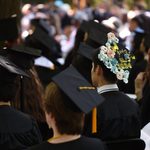 Focus on a student's graduation cap, which reads, 