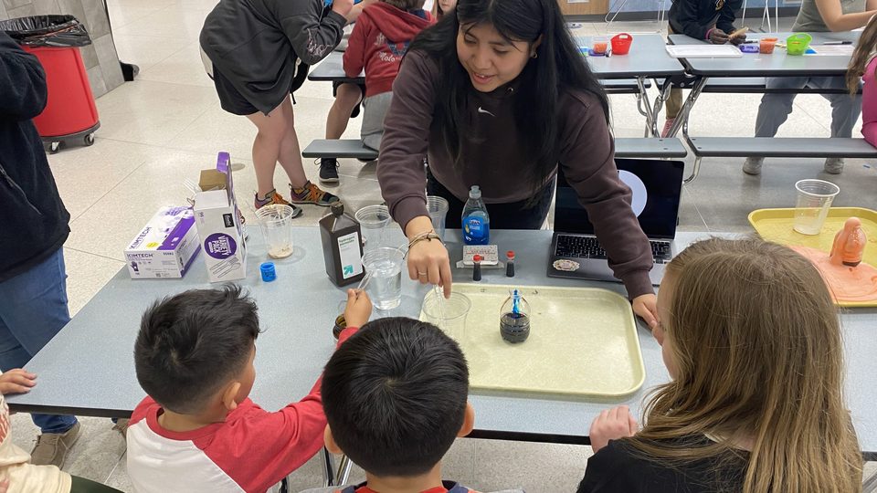 Kids work on a science project with the help of a Carleton student
