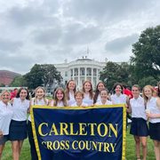 The Carleton women's cross country team in front of the White House, in matching uniforms and holding a banner reading, 