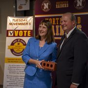 Carleton President Alison Byerly and Northfield Public Schools Superintendent Matt Hillmann pose for a photo with a brick from a previous school construction project.