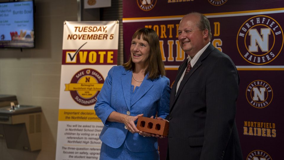 Carleton President Alison Byerly and Northfield Public Schools Superintendent Matt Hillmann pose for a photo with a brick from a previous school construction project.