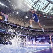 Matt Wilkinson ’21, mid-jump over the water steeplechase barrier during the 2024 Olympics, seen from the ground.