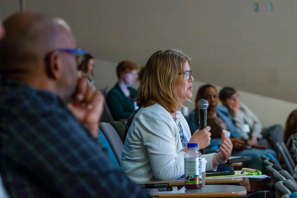 One person in an audience asks a question into a microphone.
