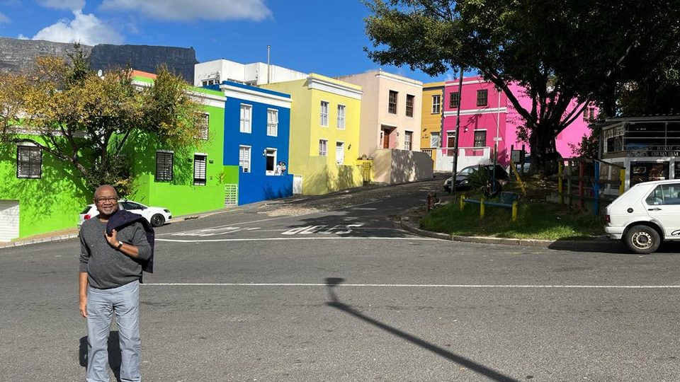 Chérif Keïta standing in front of a row of colorful houses.