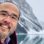 Selfie of Francis Su in front of snowy mountains and a lake.