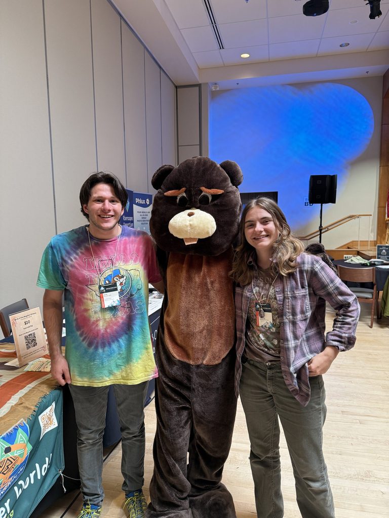 Two Carleton students pose with someone in a beaver mascot suit.