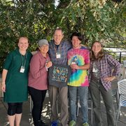 Five people pose outdoors with a BeaverCON tote bag.