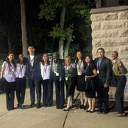 Ten students pose together in a line, all wearing professional clothing and lanyards.
