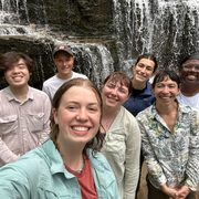 A group of students take a selfie in front of a waterfall.