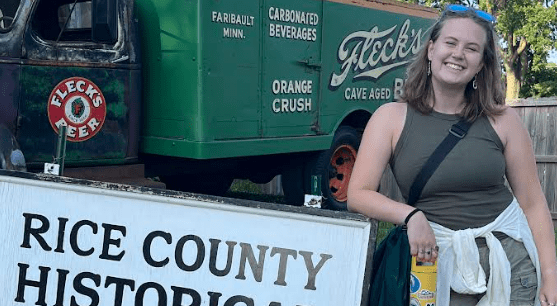 Lily Burrows '26 next to a Rice County sign during the Rice County Fair in July.