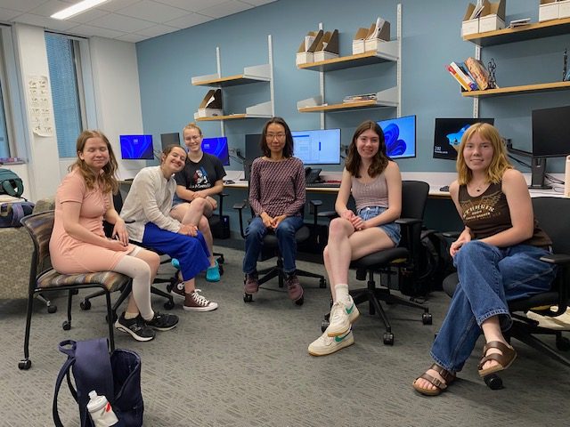 A group of students smiling at the camera in a computer lab