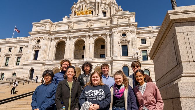A group of students stand in front of the Minnesota state capitol building.