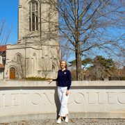 Anna Ursin ’25 standing in front of the Carleton sign by the Chapel.