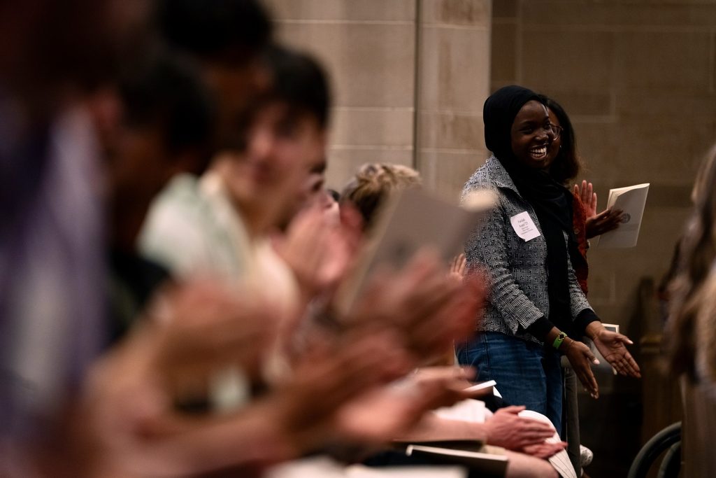 A student stands up in an applauding crowd at Honors Convo.