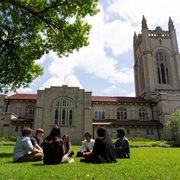 A group of students sit in a circle by the Chapel on a sunny day.