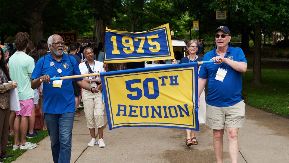 Two people carry a banner reading, 