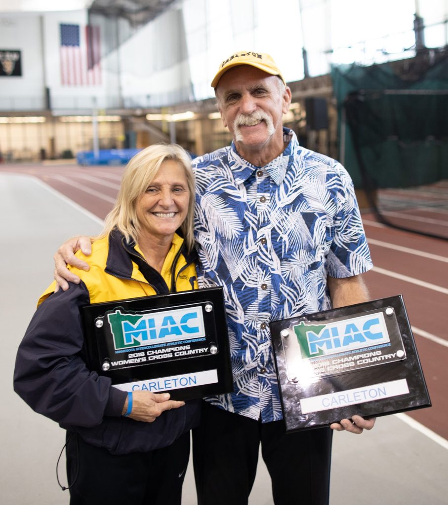 Donna and Dave Ricks pose with their respective women's and men's 2018 cross country MIAC champions plaques.