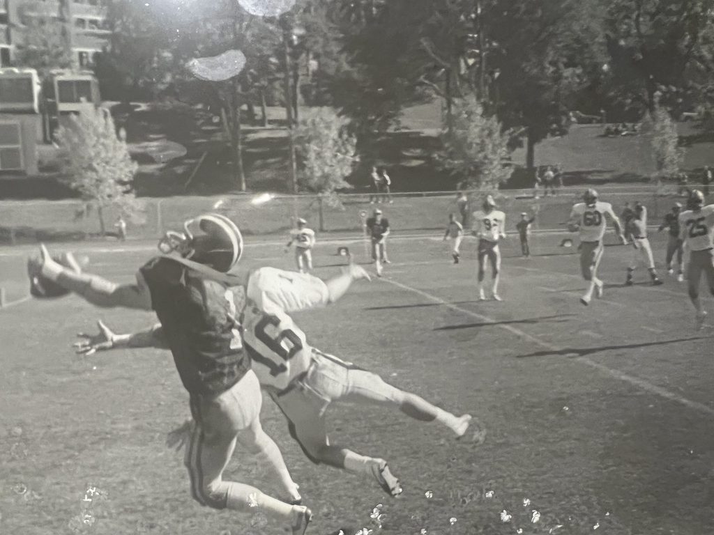 Black and white photo of a student catching a football during a game.