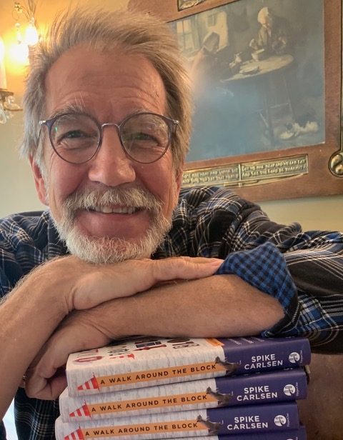 Spike Carlsen, leaning his arms and head on a stack of his books.