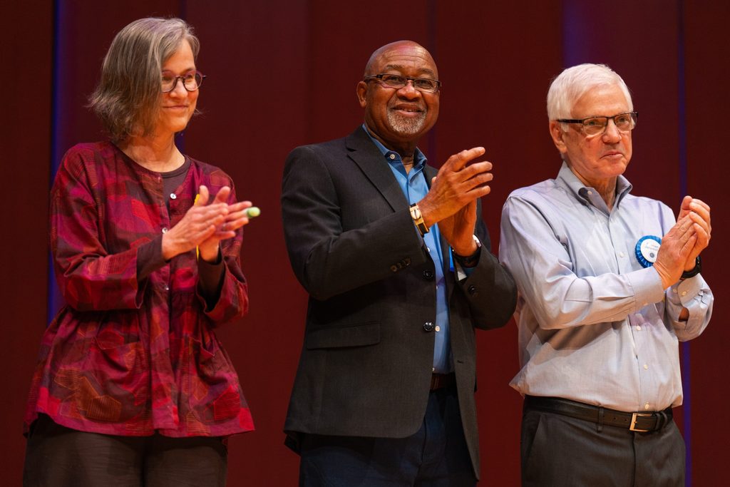 Mary Ann Kelling, Chérif Keïta, and Fernán Jaramillo, clapping and standing on the Kracum stage.