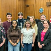 A group of students and professionals pose in a court room.