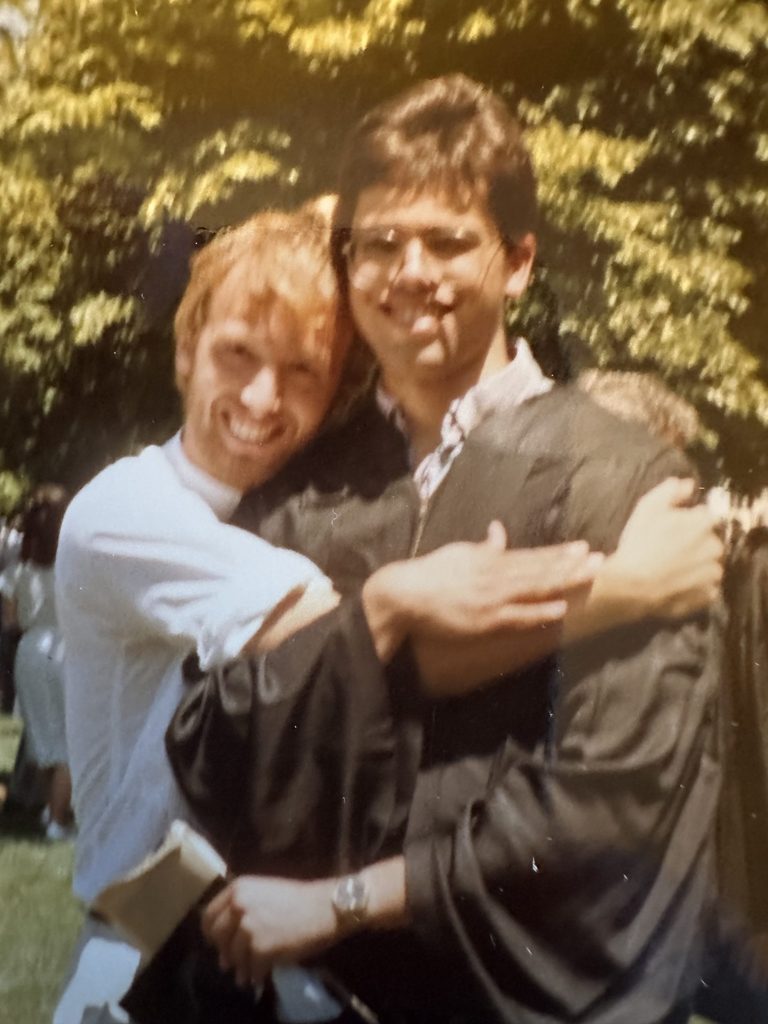 Dan Tysver hugs David Wallace-Jackson, who is wearing graduation robes.