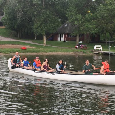 Seven happy RAs in a canoe on a lake.