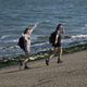 Two girls walk alongside the ocean