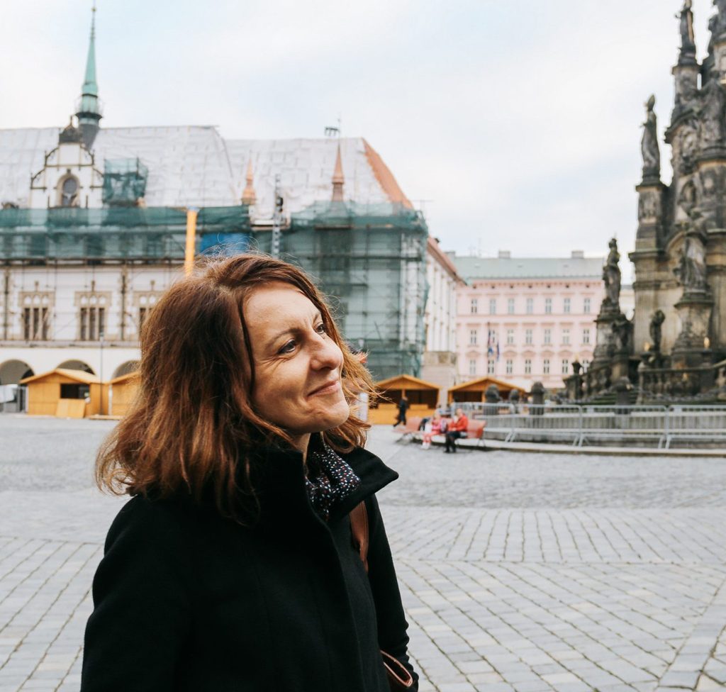 Professor smiling, looking on, into front of European building