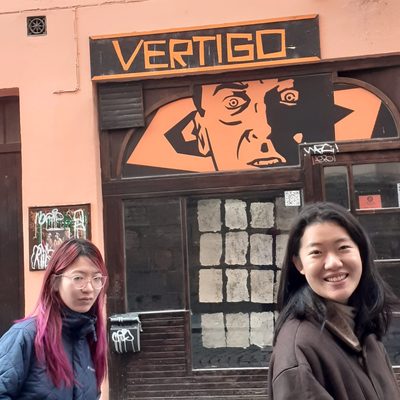 Two students stroll in front of a pink establishment called 