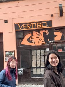 Two students stroll in front of a pink establishment called "Vertigo"