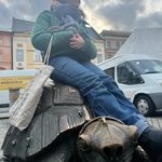 Student relaxes on a bronze statue of a giant turtle in Prague