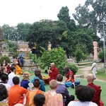 Students listen to a monk speaking outside