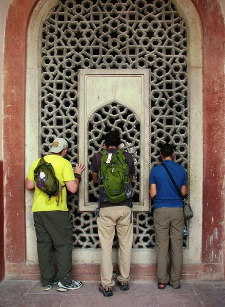 Three students peer into the window at Hamayun’s Tomb in India
