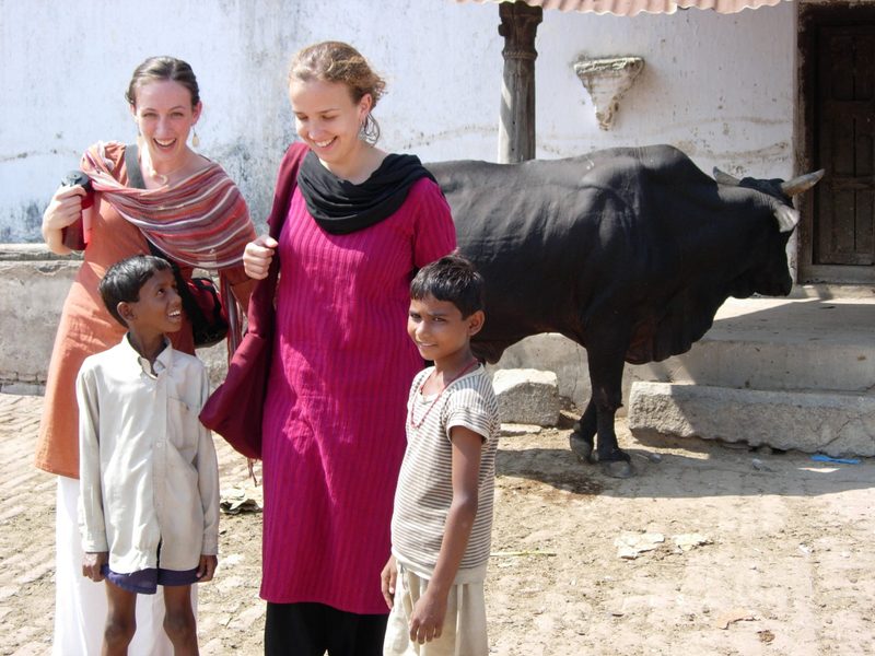 Students pose with children and a cow