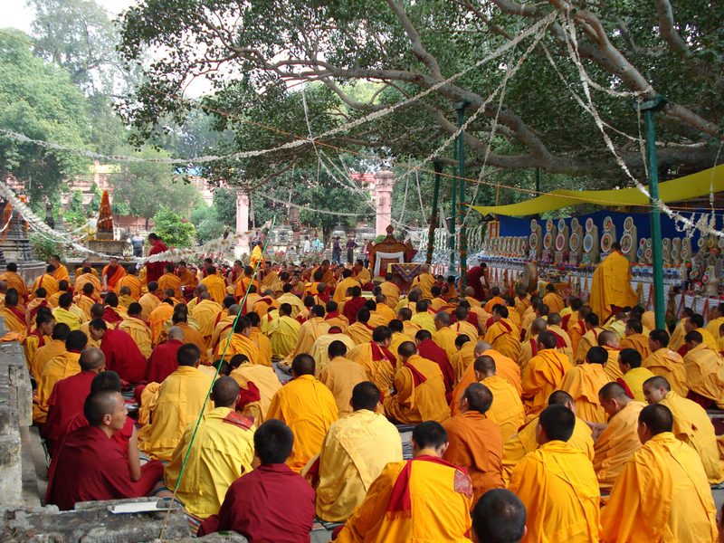 A large group of yellow-clad monks gather outdoors