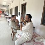 Two students relax on the day beds at Burmese monastery. One is playing a flute, the other a mouth harp.