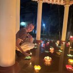 Student lights lotus flower candles in the evening in Bodhgaya