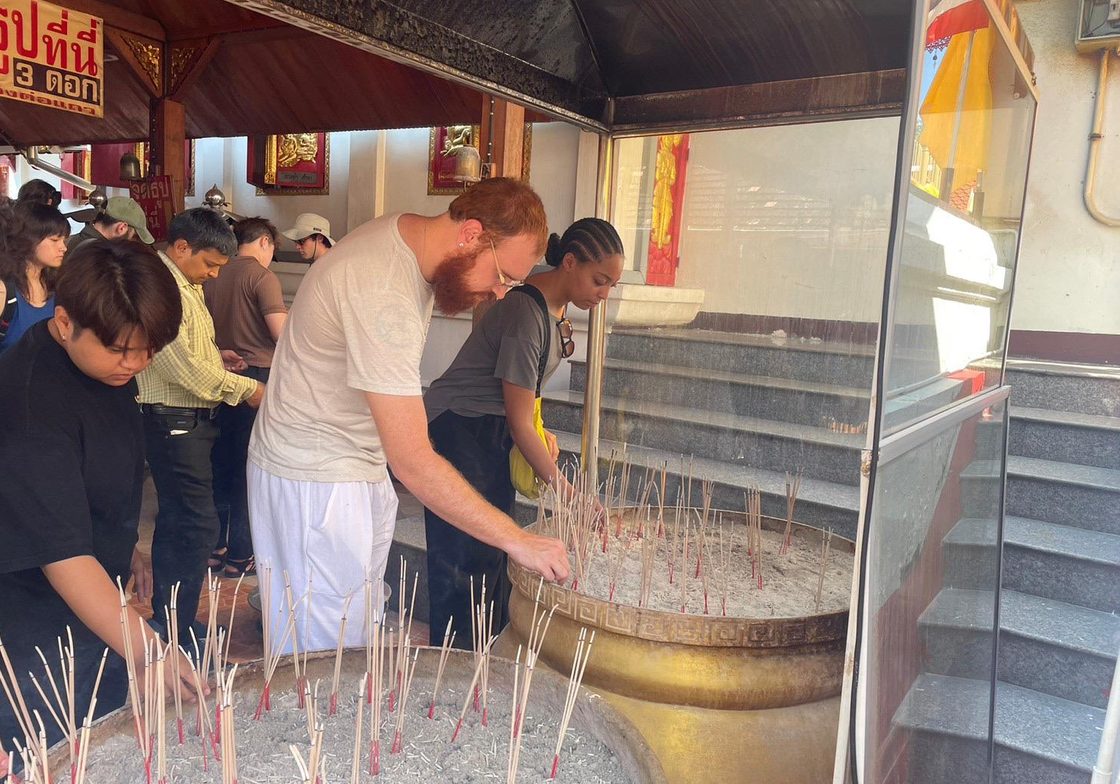 Students lighting sticks of incense outside a Buddhist temple in Thailand