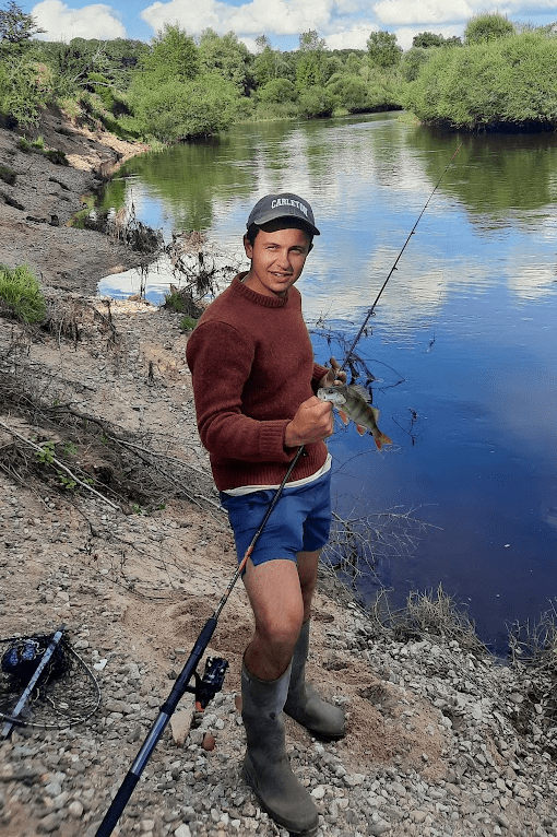 Daniel McGovern holding fishing gear on the bank of a river
