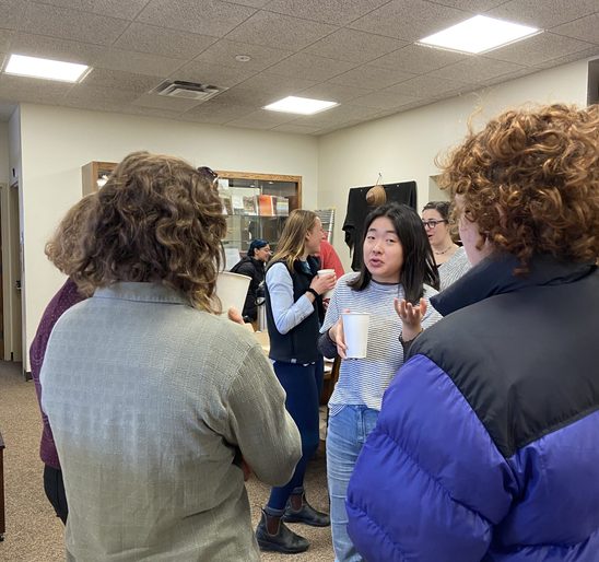 A group of SOAN students conversing in the SOAN lounge at the winter '23 End-Of-Term Party.