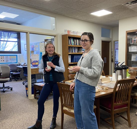 Two SOAN students conversing and enjoying pastries in the SOAN lounge at the winter '23 End-Of-Term Party.
