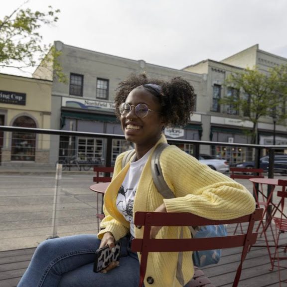 Ayanna sitting in a chair, smiling at the camera.